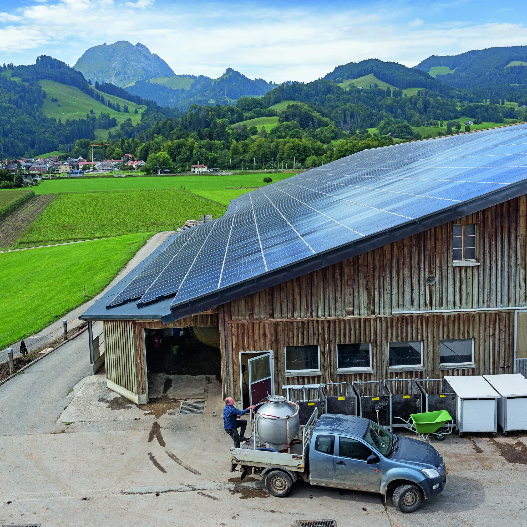 Ein Landwirtschaftsbetrieb in einer typischen Schweizer Landschaft; das riesige Dach ist mit Sonnenkollektoren bedeckt.